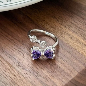Detailed macro view of silver open ring with purple heart-shaped stone butterfly