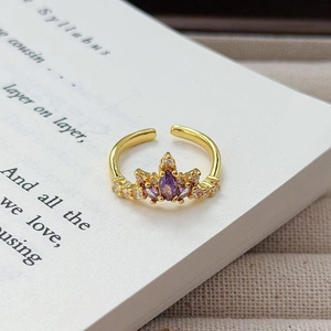 Makro-Detail des Vintage-Goldkronenrings mit lila Zirkon auf antikem Buch