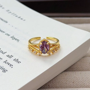 Nahaufnahme eines Vintage-Goldrings mit lila Zirkon auf einer Buchseite als Hintergrund
