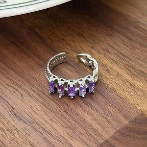 Close-up of adjustable silver ring with five purple rectangular zircons on wood