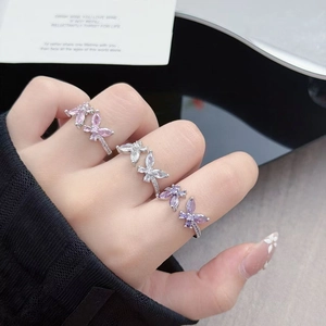Detailed view of silver butterfly zircon rings in pink, white, and purple on hand