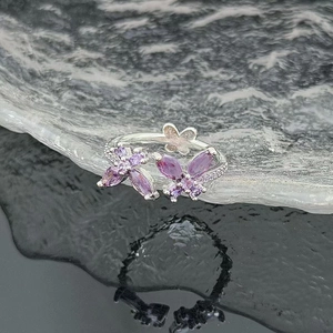 Detailed macro view of silver butterfly ring with purple zircons over water ripple surface