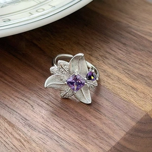 Macro view of silver floral ring with square purple zircon and fine brushed texture