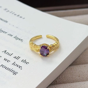 Nahaufnahme eines goldenen Vintage-Rings mit lila Edelstein und Federblattgravur
