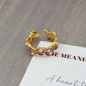 Detail van een vintage gouden ring met paars emaille vlinder en witte kunstparels
