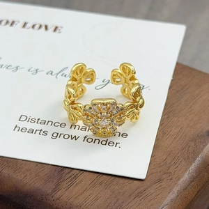 Vue détaillée d'une bague florale dorée vintage avec zircons sur socle en bois