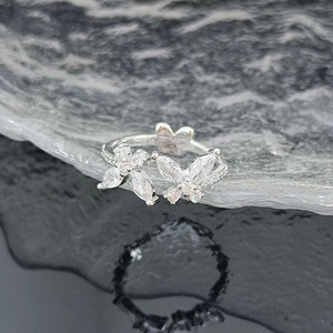Detailed close-up of butterfly zircon ring with silver floral pattern and sparkles