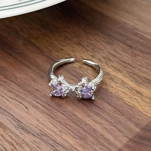 Detail view of silver bow ring with marquise purple crystals on a dark wood table