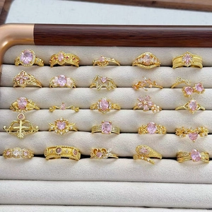 Collezione di anelli dorati vintage con zirconi rosa e motivi floreali su vassoio