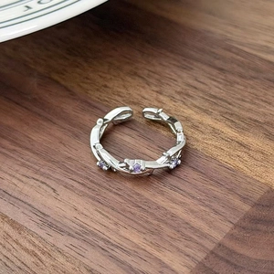 Macro shot of branch-shaped silver ring with purple zircon stones on a wooden background