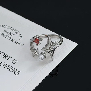 Nahaufnahme eines Star-Punk-Rings mit rotem Zirkon und Perle auf einer minimalistischen Karte
