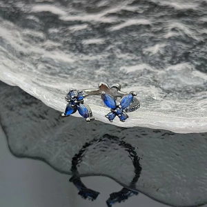 Detailed close-up of blue butterfly zircon open ring with black metal finish and pavé setting