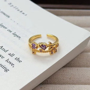 Nahaufnahme eines Vintage-Goldrings mit lila herzförmigem Zirkon auf einer Buchseite