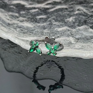 Macro detail of dual butterfly open ring with green zircon and black plated finish