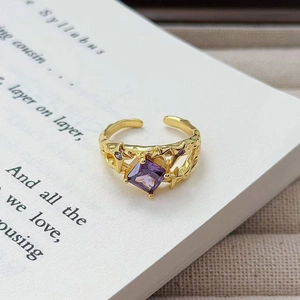 Makro-Detail des Vintage-Goldrings mit lila Zirkon auf antiken Buchseiten