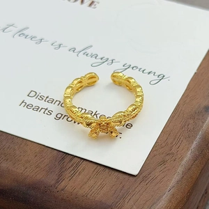 Gros plan d'une bague nœud dorée vintage avec texture givrée sur surface en bois