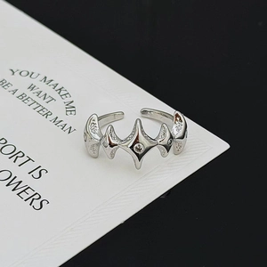 Nahaufnahme eines Starburst-Punkrings mit Zirkonia auf weißer Karte vor schwarzem Grund