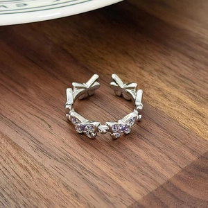 Detailed close-up of a silver butterfly ring with purple zircons on a wooden table