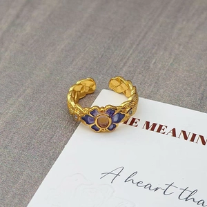 Detail van een vintage gouden gevlochten ring met paarse emaille bloem en kristallen