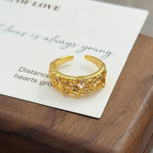 Détail macro d'une bague vintage dorée avec oiseaux ciselés, fleurs et zircons incrustés
