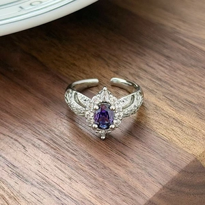 Macro shot of silver ring with oval purple gemstone and pave-set white zircon stones