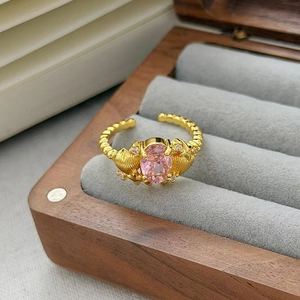 Dettaglio dell'anello regolabile con zircone rosa e motivi a conchiglia in oro lucido