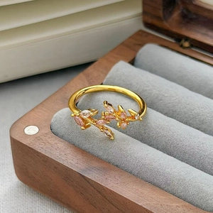 Dettaglio dell'anello vintage dorato con zirconi rosa e foglie su scatola in velluto