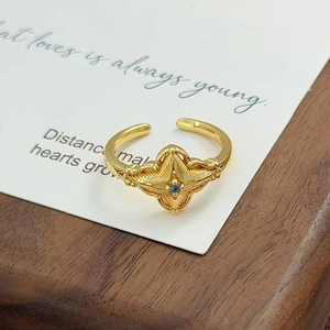 Gros plan sur une bague vintage dorée avec étoile à quatre branches et zircon bleu