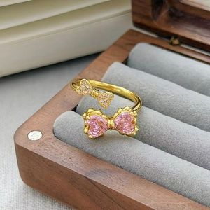 Dettaglio anello vintage in oro con pietre a cuore rosa e fiocchi di zirconi lucenti