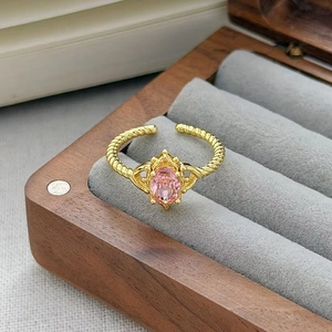 Dettaglio macro di un anello vintage dorato con gemma rosa ovale e montatura a corona