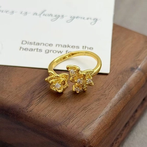 Détail macro d'une bague vintage dorée aux motifs floraux et zircons sur du bois