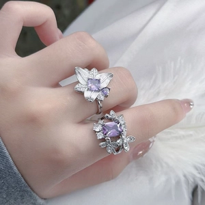 Close-up of elegant silver flower rings with purple zircon stones on woman finger