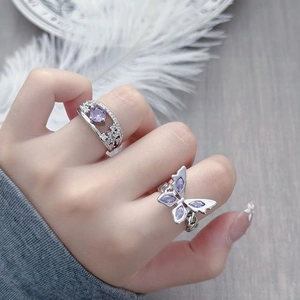 Detail of silver ring set with purple zircon butterfly and crystal studded wide band