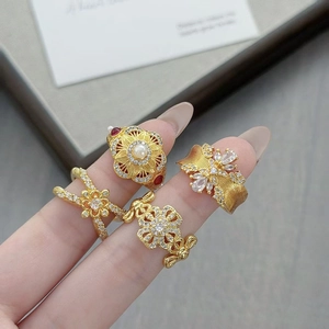 Gros plan sur des bagues vintage dorées avec perles, zircones et motifs floraux