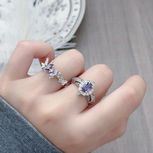 Detail of silver rings featuring purple zircon butterfly and oval stone with floral textures