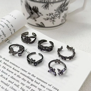 Ensemble de bagues papillon noir vintage avec pierres violettes sur un livre ouvert
