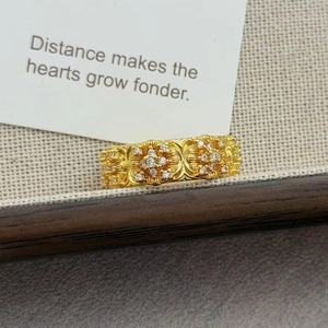 Gros plan d'une bague vintage dorée avec relief floral et zircons sur fond texturé