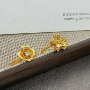 Détail de deux bagues florales dorées vintage avec incrustation de zircon sur tissu texturé