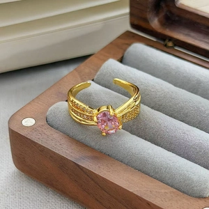 Dettaglio di un anello con gemma rosa ovale e fasce dorate multistrato con piccoli diamanti