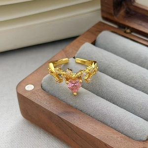 Macro di un anello con cuore di zircone rosa e pavé di diamanti in scatola di legno