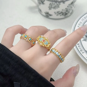 Vue détaillée de bagues vintage plaquées or avec motifs floraux en émail et design évidé