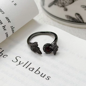 Gros plan d'une bague papillon gothique avec pierre rouge sur une page de livre ancien