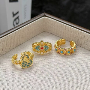 Détail macro de bagues dorées vintage avec émail fleuri et gourde dans un écrin