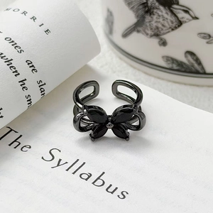 Vue macro détaillée d'une bague papillon en émail noir avec des pierres précieuses sombres