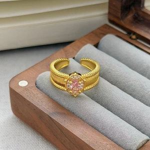 Dettaglio anello vintage dorato con zircone rosa e fascia con trama a spirale retrò