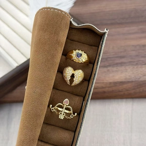 Dettaglio di tre anelli vintage dorati con pietre a cuore in una scatola di velluto marrone