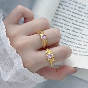 Primo piano di anelli d'oro vintage con zirconi rosa su sfondo di pizzo bianco