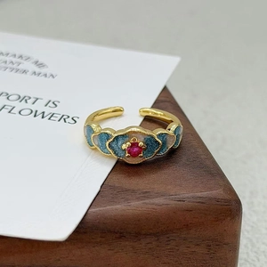 Détails d'une bague fleur vintage avec émail dégradé et incrustation de pierre rouge