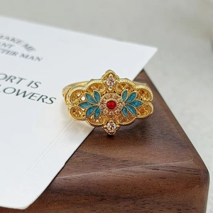 Détail d'une bague vintage en émail avec filigrane d'or, gemme rouge et motifs fleurs