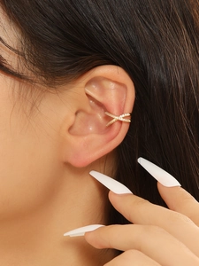 Close-up of a gold criss-cross ear cuff with micro-pave cubic zirconia on model ear